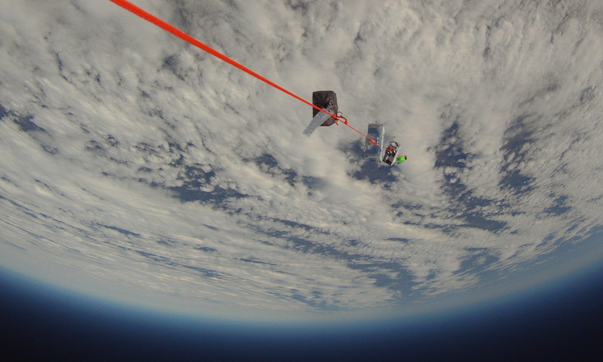 Downward view showing balloon payload string with Earth and its horizon below.