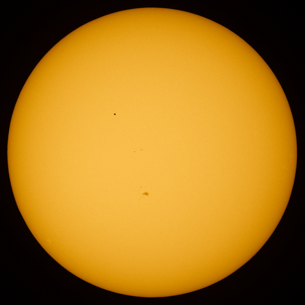 Image of Mercury in transit across the Sun in 2016, by Elijah Matthews via Wikipedia.com - flipped vertically to emphasize the silhouette of Mercury instead of the sunspot group also present.