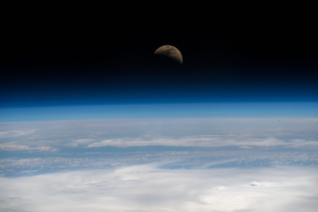 First quarter moon over Earth's limb; photo taken from ISS.